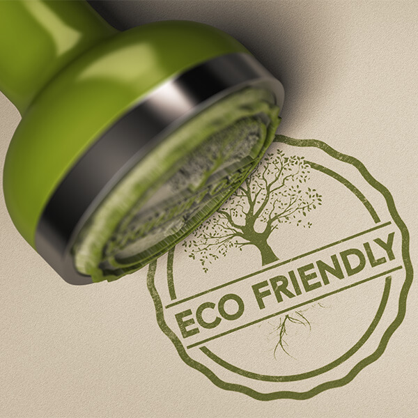 Text: Ein dunkelgrüner Stempel mit dem Aufdruck ECO Friendly, auf Recycling Papier. 